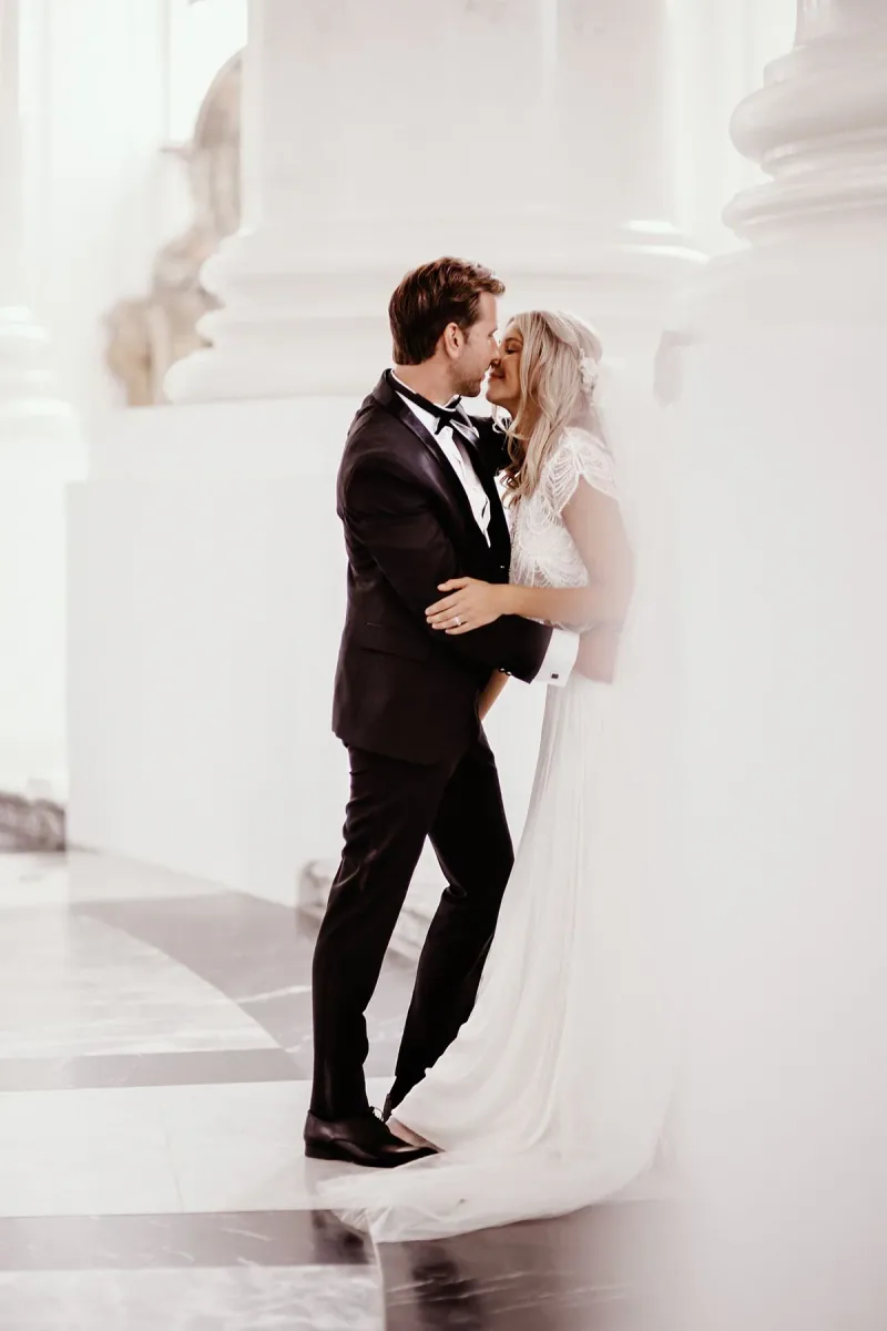 Ein Hochzeitspaar steht zwischen den hellen Säulen einer Kirche